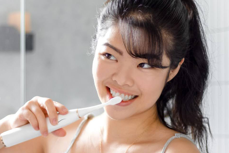 Woman brushing her teeth using Colgate Electric toothbrush