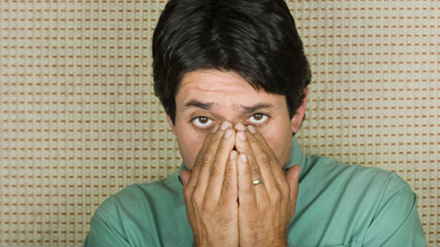 Man covering his nose and mouth with his hands.